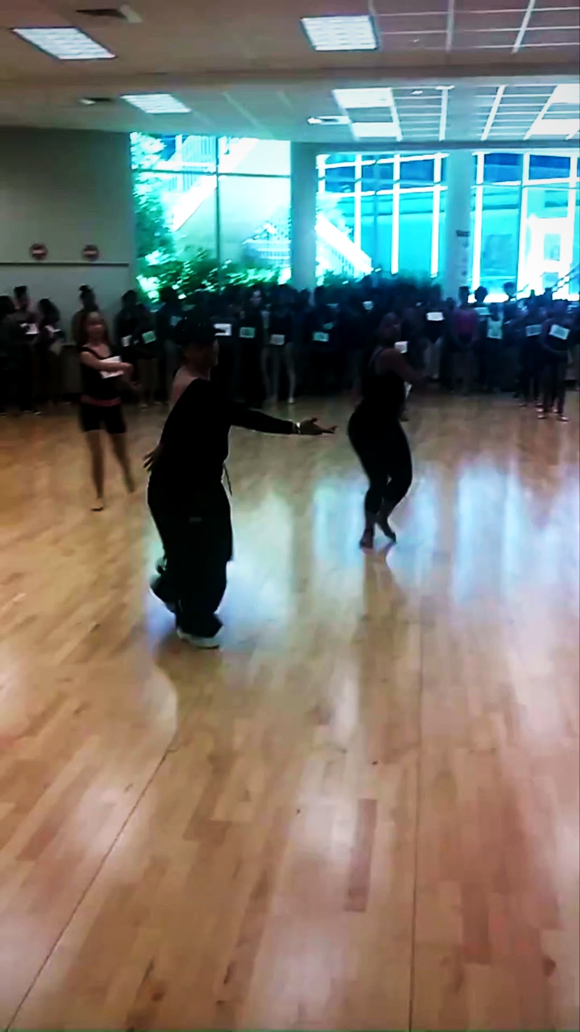 RikkiTheFool leading movement in a dance studio with dancers gathered behind