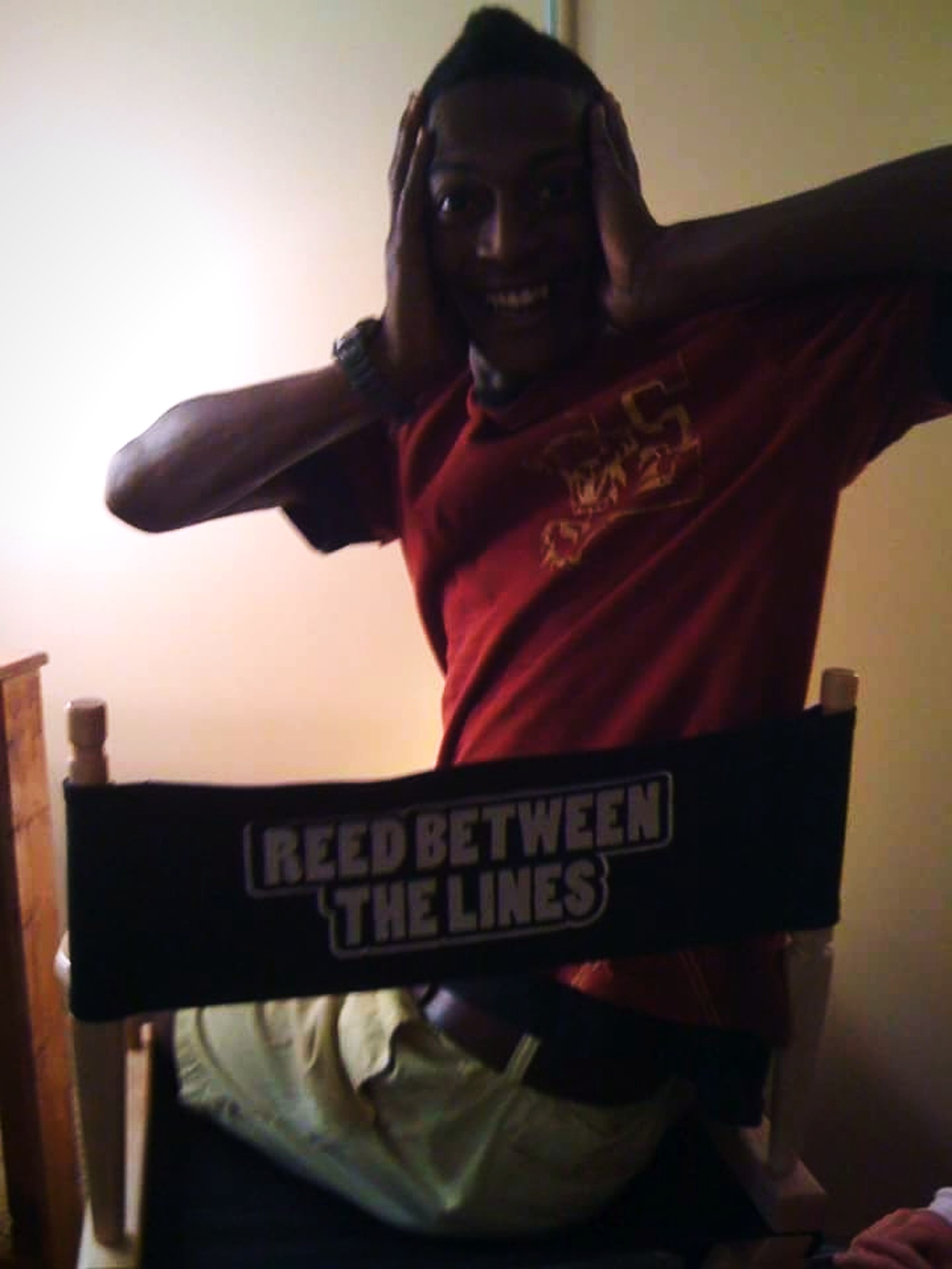 RikkiTheFool playfully posing in a Reed Between the Lines director's chair