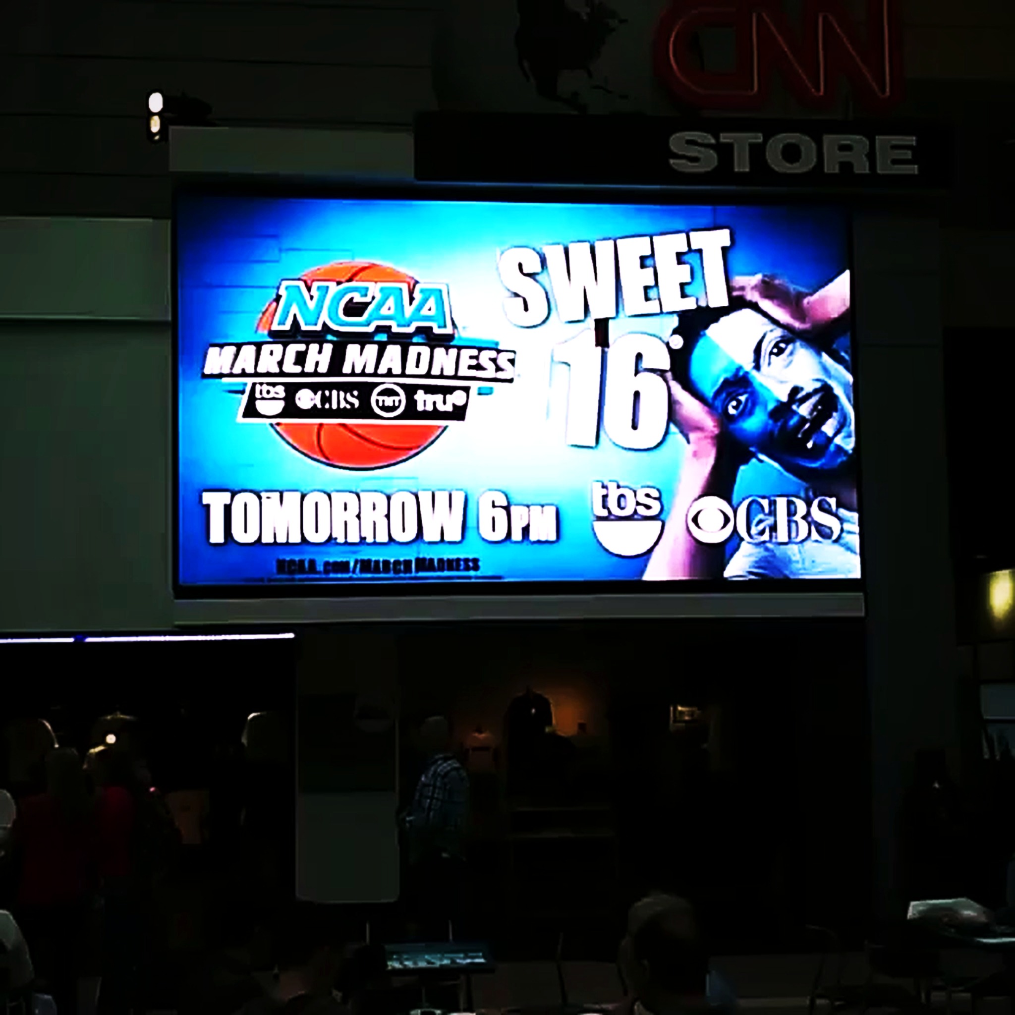 CNN Center big screen displaying an NCAA March Madness Sweet 16 campaign featuring RikkiTheFool